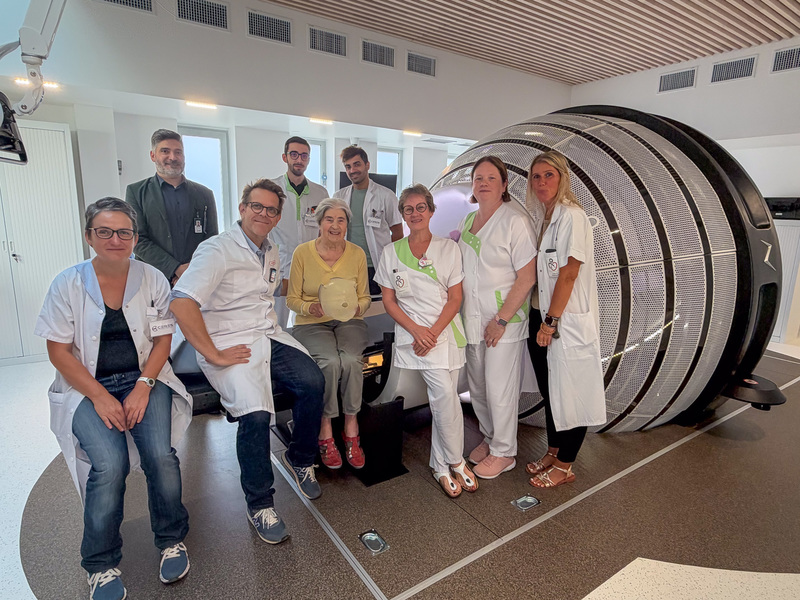 Photographie de la première patiente assise sur le ZAP-X aux côtés de l'équipe médico-soignante